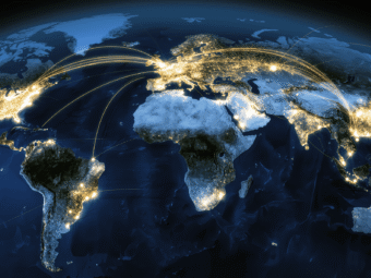 Aerial view of global IoT device network with glowing data streams connecting cities worldwide